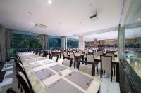 Un comedor con mesas y sillas y ventanas. en Royal Prince Resort Pattaya, en Pattaya South