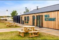 een groep picknicktafels voor een gebouw bij Aurora on the Dunes- Cozy Coastal Retreat with Scenic Views in Lossiemouth
