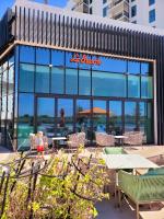 um restaurante com mesas e cadeiras em frente a um prédio em Luxury Waterfront 3BR, Pool, Canal Views! Yas Island em Abu Dhabi