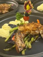 een bord eten met een stuk vlees en groenten bij Hill Garden Resort Hotel in San Ignacio