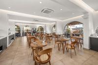 Un restaurante con mesas y sillas de madera y ventanas. en Cabana White Boutique Hotel, en Kardamaina