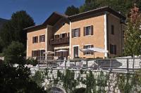 a building with tables and umbrellas in front of it at La Villa degli Orti in Borgo