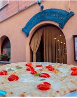 La Locanda Del Brolio في Cantiano: بيتزا عليها طماطم أمام مبنى