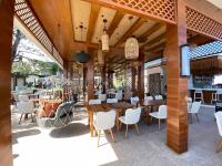 eine Terrasse mit Tischen und weißen Stühlen und einer Bar in der Unterkunft Manggadiwa Resort and Spa in Tando