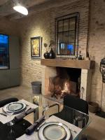 een woonkamer met een open haard en een tafel en stoelen bij Le Clos 1855 in Saint-Laurent-des-Bâtons