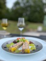 een bord met vlees en groenten en een glas wijn bij Le Clos 1855 in Saint-Laurent-des-Bâtons