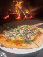 une pizza sur une assiette dans un four à bois dans l'établissement The Horatio Motel Mudgee, à Mudgee