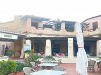 een buitenterras met tafels, stoelen en een parasol bij Casa di Bella in Santa Teresa Gallura