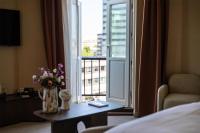 a hotel room with a window with a vase of flowers on a table at NH Copenhagen Grand Joanne in Copenhagen