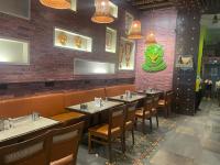 a restaurant with tables and chairs and a brick wall at Zense Candolim in Candolim
