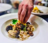 uma pessoa espalhando queijo em um prato de comida em Gasthaus Tschiffra em Blitzingen