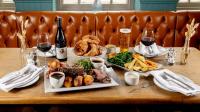 a table with two plates of food and glasses of wine at The Eaton Oak in Saint Neots