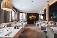um restaurante com mesas e cadeiras brancas e um lustre em Boutique Hotel Mandarfnerhof em Sankt Leonhard im Pitztal