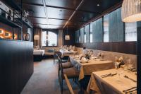 uma sala de jantar com mesas, cadeiras e janelas em Boutique Hotel Mandarfnerhof em Sankt Leonhard im Pitztal