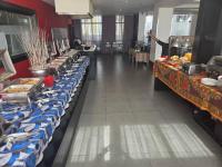 Una línea de buffet con mesas azules y blancas y un camarero. en Onomo Hotel Dar es Salaam, en Dar es Salaam