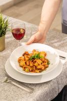 una persona che prende un piatto di pasta con un bicchiere di vino di Hotel Lux a Gabicce Mare