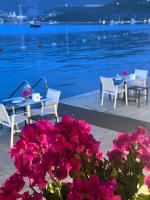 een tafel, stoelen en bloemen naast het water bij UMAYRA OTEL in Bodrum City