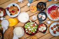 WellClub - Family Wellness & Sea View Suites في بافوس: طاولة خشبية مليئة بالكثير من الأطباق من الطعام