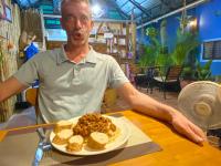 贡布Derm Svay Guesthouse - yoga & cafe的一位男士坐在桌边，面前摆着一盘食物