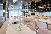 un restaurante con mesas blancas y sillas rosas en Atour Light Hotel Dalian Xinghai Square Hang Lung Shopping Center, en Dalian