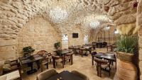 MidyatにあるKonak Zenobiaのテーブルと椅子と石の壁があるレストラン
