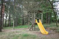 a playground with a yellow slide in the woods at La Ptite Ferme de Caro in Meyrignac-lʼÉglise