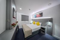 Dormitorio pequeño con cama con almohadas amarillas en Ilford Hotel Goodmayes, en Ilford