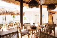 a restaurant with tables and chairs and straw umbrellas at Antana Hotel in Canggu