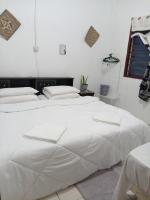 two beds in a room with white sheets at Mulu D Cave Homestay Room 2 in Mulu