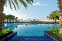 ein großer Swimmingpool mit Palmen und Gebäuden in der Unterkunft Rixos The Palm Hotel &amp; Suites - Ultra All Inclusive in Dubai