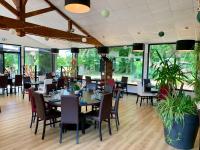 a dining room with tables and chairs and windows at Terres de France - Natura Resort Pescalis in Moncoutant