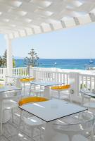 un patio con mesas y sillas con el océano en el fondo en The George Hotel Mykonos, en Platis Gialos