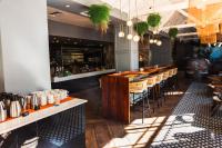 a bar with wooden tables and chairs in a restaurant at ONOMO Hotel Cape Town – Inn On The Square in Cape Town