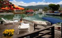 a dock with chairs and a boat in the water at Angra Boutique Hotel in Angra dos Reis