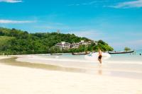 a man walking on the beach with a surfboard at Happy Place Official in Nai Yang Beach