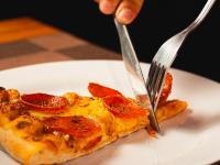 a person cutting a slice of pizza with a fork and knife at VELINN Pousada Bromelias in Ilhabela