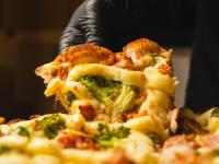 a person eating a slice of pizza with broccoli at VELINN Pousada Bromelias in Ilhabela