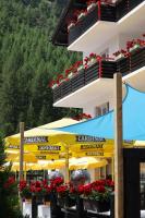 a building with yellow umbrellas and red flowers at Hotel Restaurant Mattmarkblick in Saas-Almagell