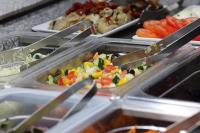 a buffet of food with tongs and vegetables at Hotel Restaurant Mattmarkblick in Saas-Almagell