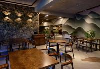 Un restaurante con mesas y sillas y una pared de piedra. en Dilijan Inn Hotel and Restaurant, en Dilijan