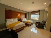una habitación de hotel con dos camas y una silla en Hotel Dali Plaza Ejecutivo, en Guadalajara
