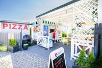 a pizza shop with a woman standing in the doorway at Dom Wakacyjny Zielone Wzgórze in Mielno