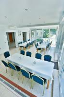 een cafetaria met witte tafels, stoelen en ramen bij Zacisze Bis in Koszelówka