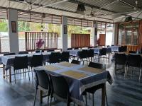 um salão de banquetes com mesas, cadeiras e janelas em Lemon Grass Resort & Spa em Havelock Island