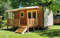 Cabaña de madera con porche y escaleras en el césped en Camping Portes d&#39;Ariege, en Pamiers