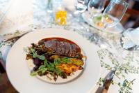 une assiette avec un steak sur une table avec des verres à vin dans l'établissement Keurusselän lomamökit, à Keuruu