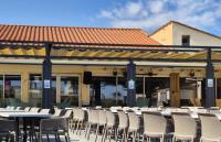 un groupe de tables et de chaises devant un bâtiment dans l'établissement Mobil- home Ohana Mar Estang, à Canet
