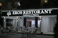 Un restaurante con mesas y sillas por la noche. en EROS HOTEL Ksamil, en Ksamil