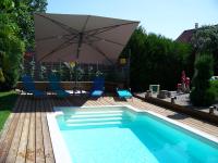 a swimming pool with an umbrella and chairs and a table at C&#39; 1 comble in Bischwihr