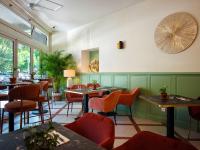 Un restaurante con paredes verdes, mesas y sillas. en Urban Style Hotel Blason du Ventoux, en Carpentras